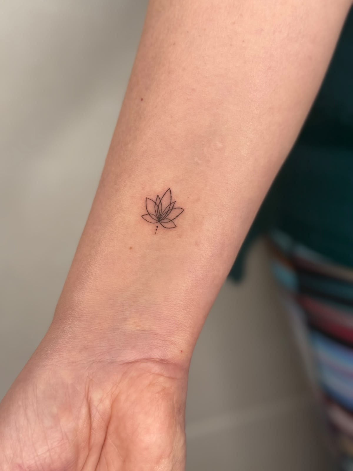 Tatuaggio fine line fiore di loto su polso